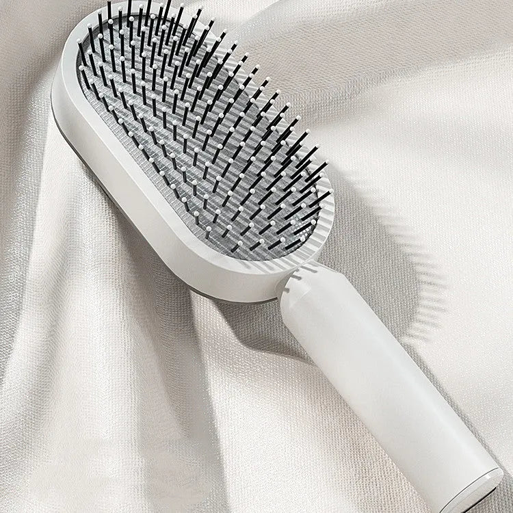 Self-cleaning air cushion hair brush in white, black gold, or black purple with ergonomic handle