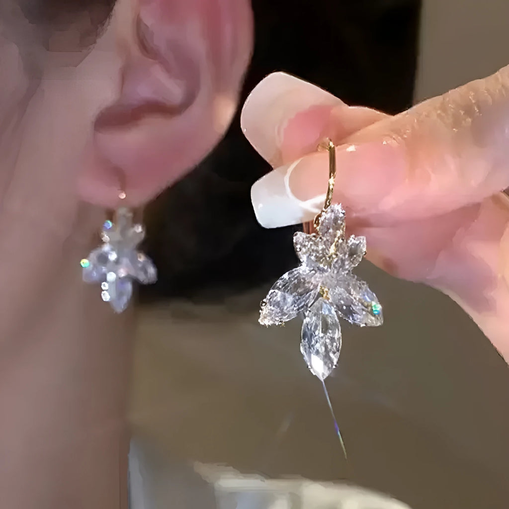 Platinum colour leaf-shaped earrings with inlaid zircon stones on white background