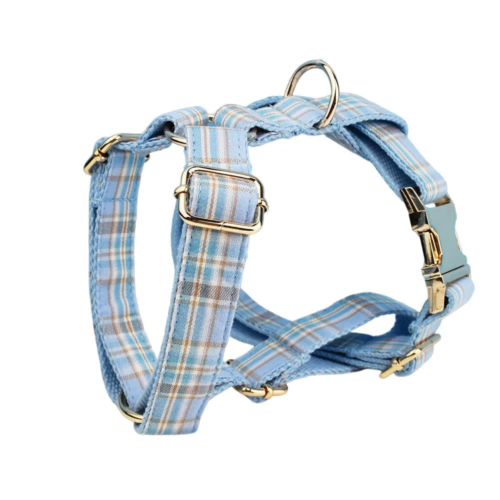 Sky blue grid forest pattern dog collar, leash, bow, and vest four-piece pet set laid out flat.