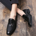 Men's black slip-on leather loafers with a pointed toe and tassel detail on a white background.