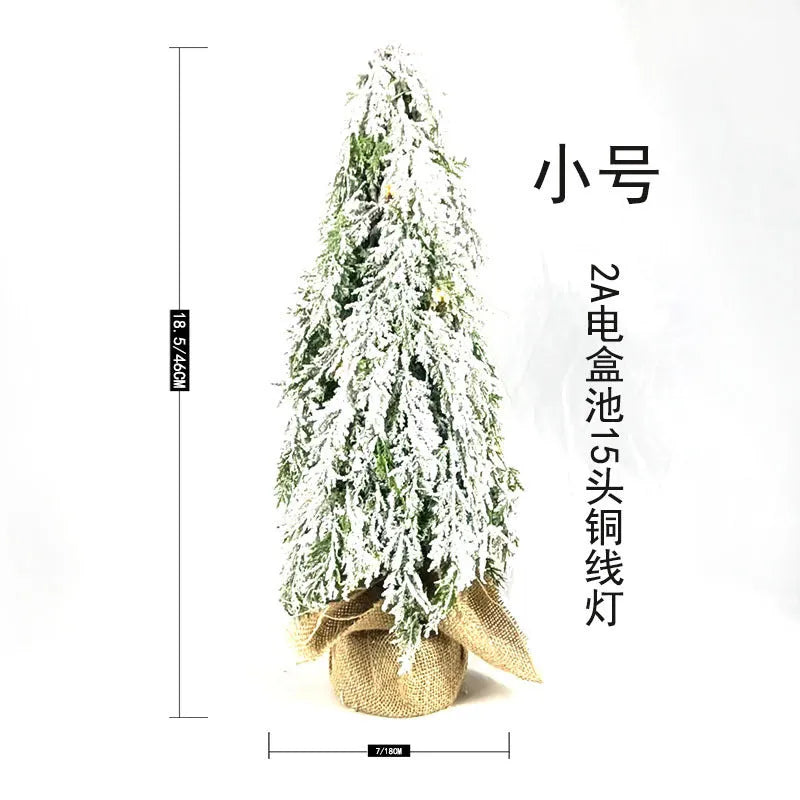 Small 24-inch artificial Christmas tree with lights and snow finish on desktop