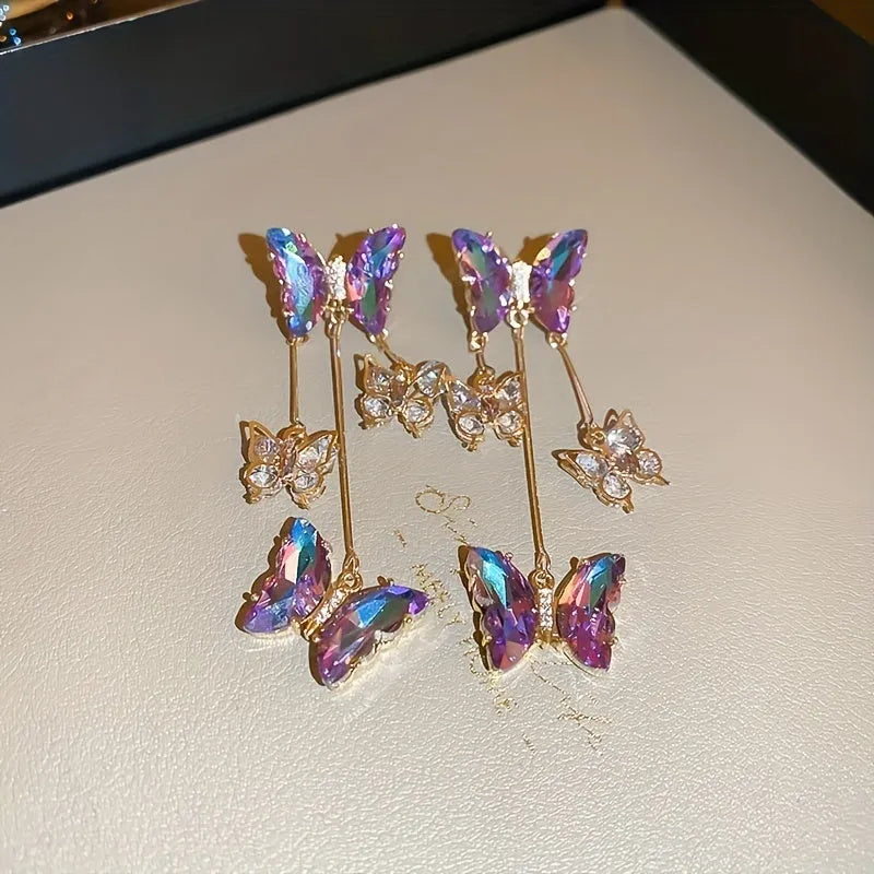 A pair of silver and blue purple butterfly tassel earrings with crystal flowers and droplet pendants.