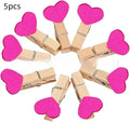 Set of five handmade solid wood heart-shaped clips in assorted colours on a wooden surface.