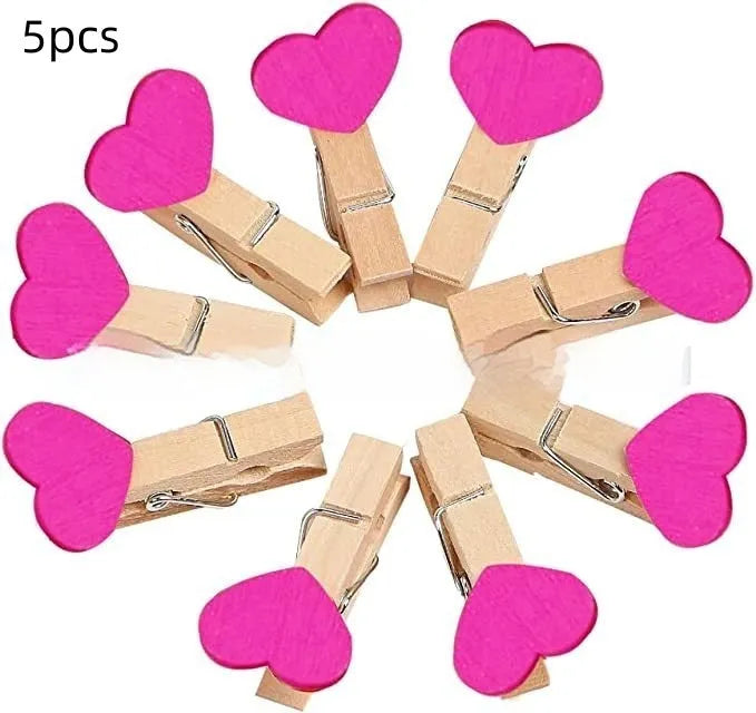 Set of five handmade solid wood heart-shaped clips in assorted colours on a wooden surface.