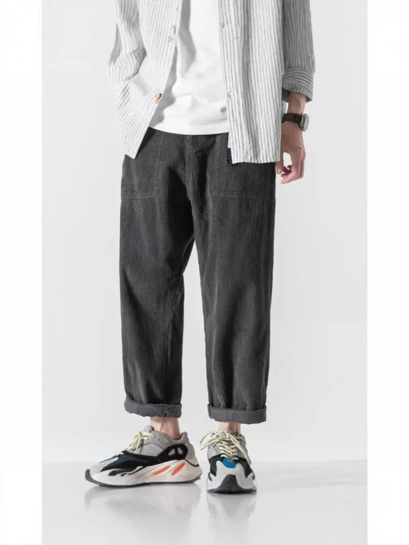 Man wearing loose straight-leg tapered trousers in dark grey, showing the full length and relaxed fit.