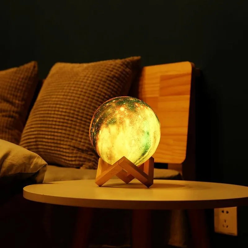 3D-printed white lunar sphere night light with crater texture on a dark surface.