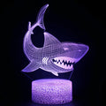 Shark-shaped 3D LED table lamp with remote control on a wooden desk.