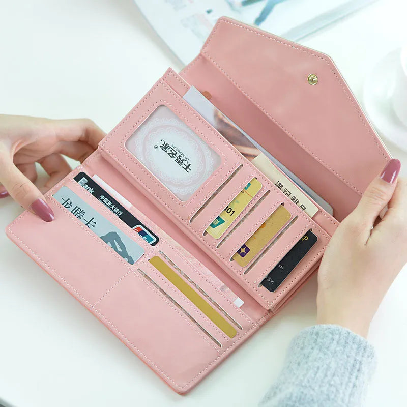 Open three-fold student wallet with buckle closure, shown in colour options on a table.