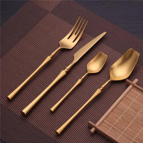 Stainless steel cutlery set with gold finish including knife, fork, spoon, and teaspoon on table