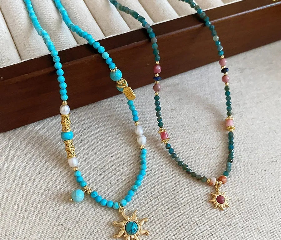 Freshwater pearl necklace with a blue stone sun pendant on an adjustable gold-toned chain.