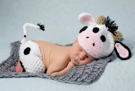White hand-knitted baby cow suit set with matching hat and trousers for newborns.