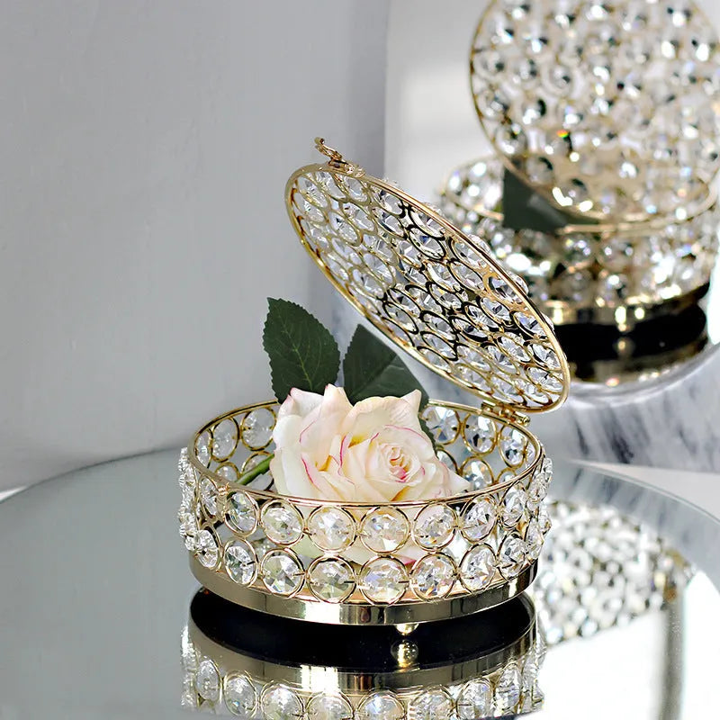 French gold iron jewelry storage box with a clear crystal glass lid on a wooden surface.
