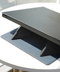 Blue or grey portable foldable laptop cooling stand bracket with anti-slip pads on a flat surface.