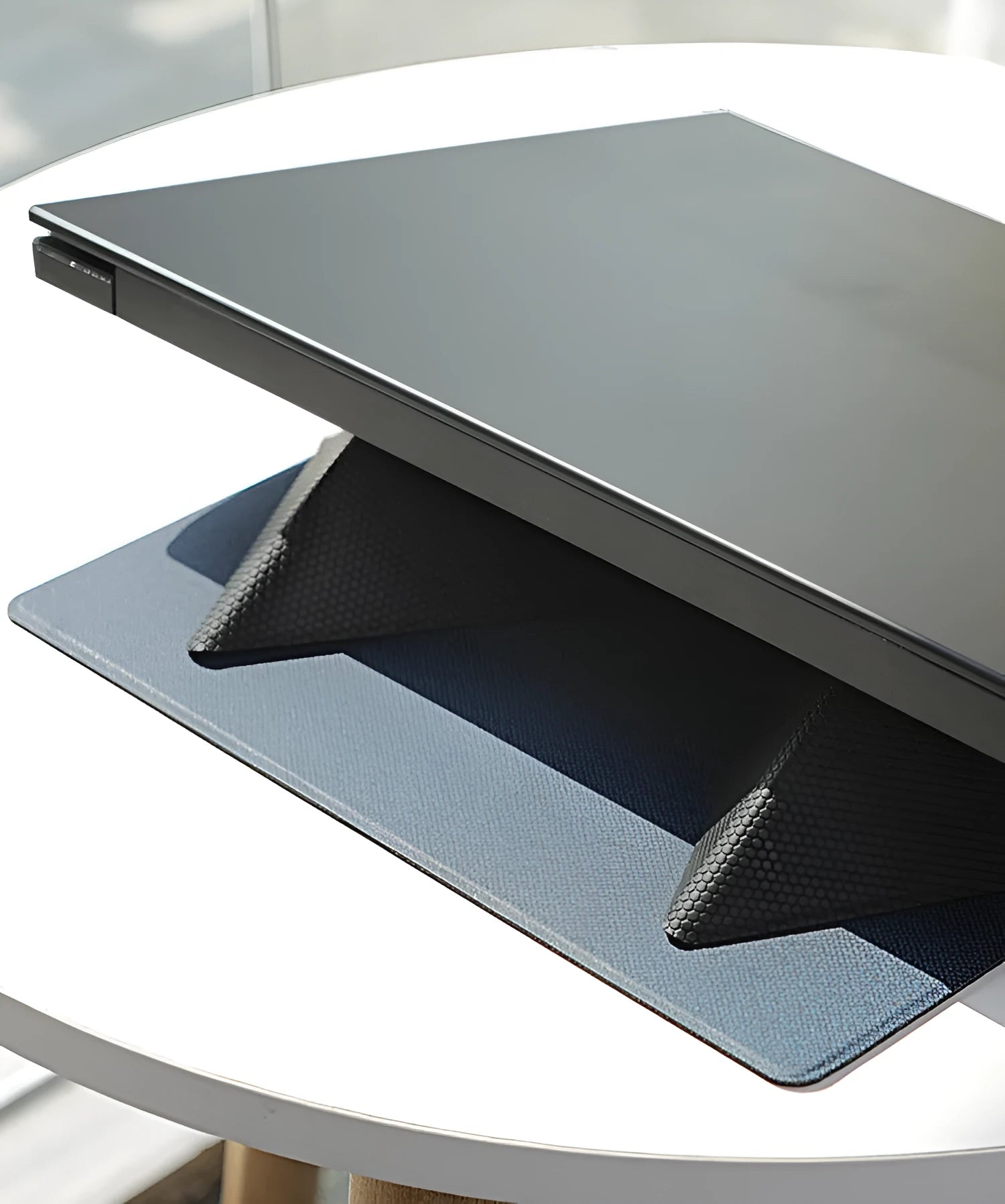 Blue or grey portable foldable laptop cooling stand bracket with anti-slip pads on a flat surface.