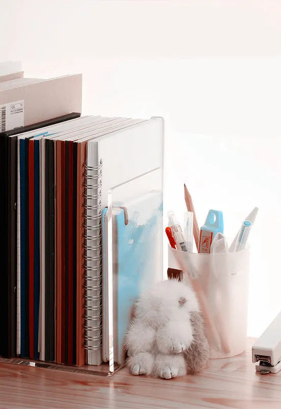 Transparent acrylic bookshelf displaying organised books on a study desk