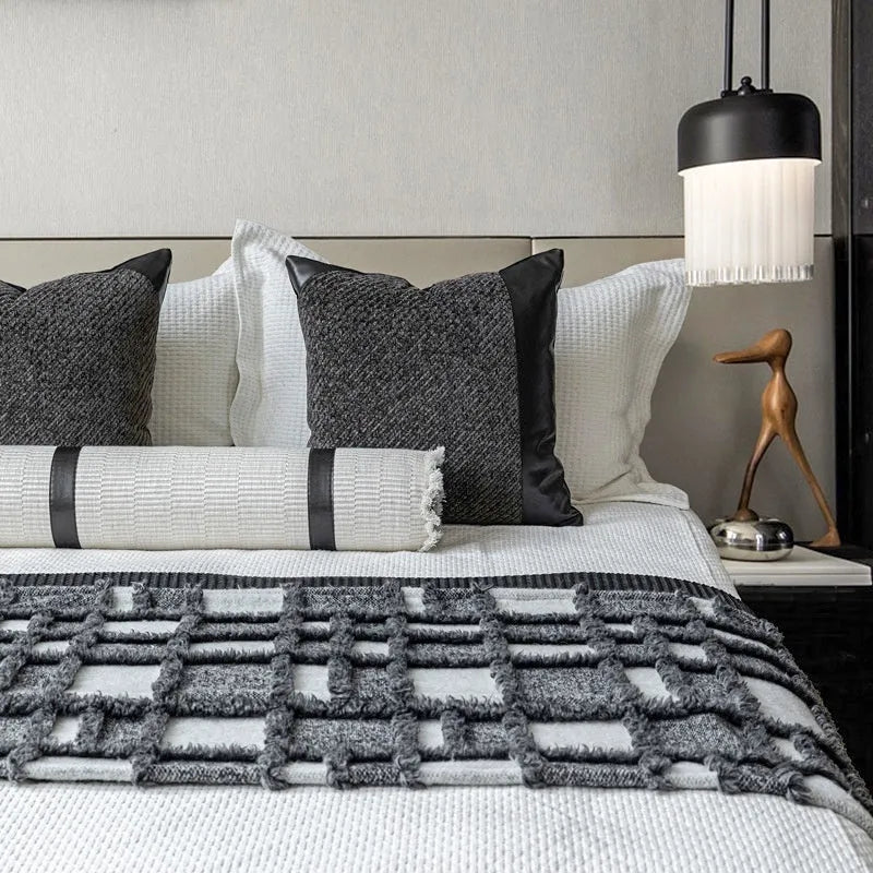 Modern minimalist grey and white plaid bed runner blanket set with a leather round pillow on a bed.