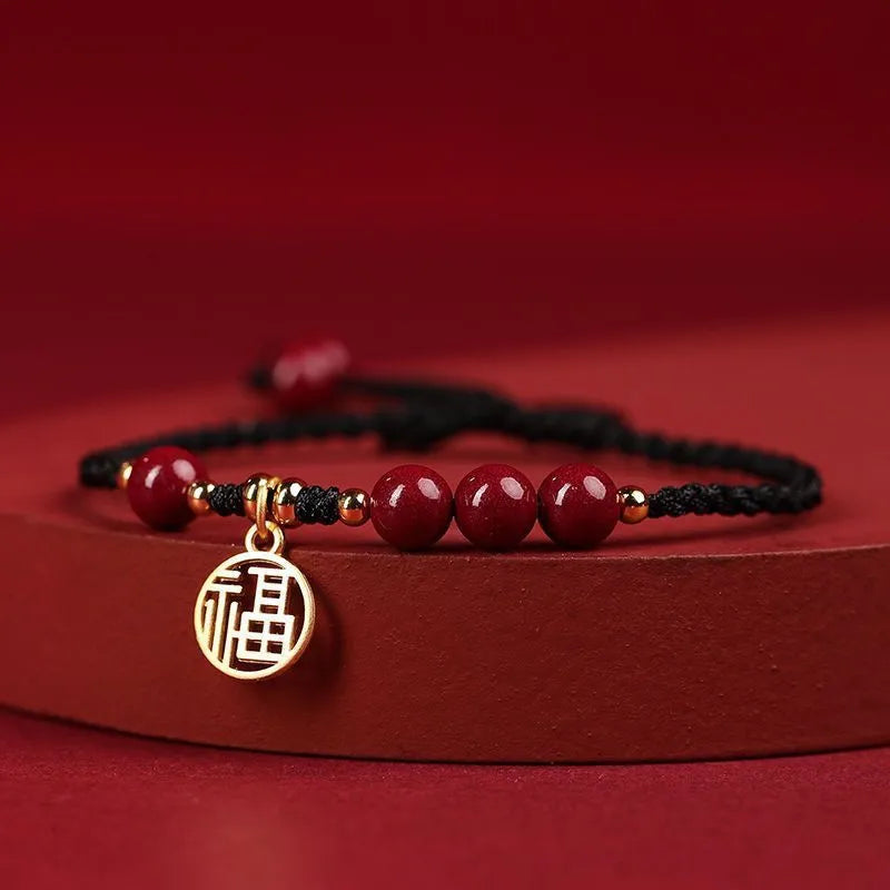 Cinnabar bracelet with braided rope in three colour options featuring round bead or flower blessing card charms