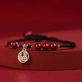 Cinnabar bracelet with braided rope in three colour options featuring round bead or flower blessing card charms
