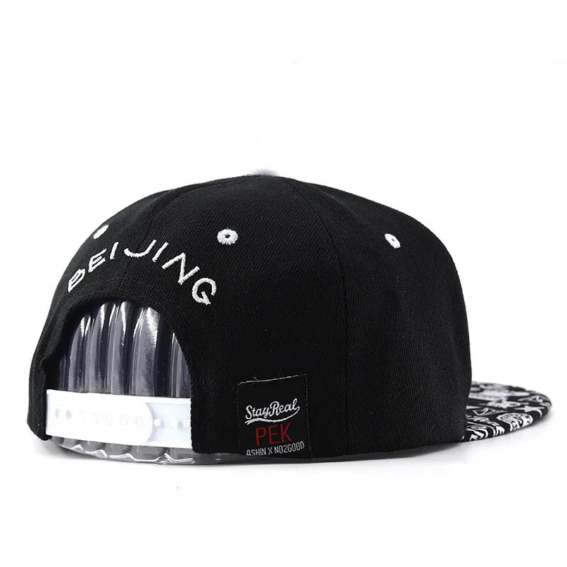 A black cotton baseball cap with embroidered lettering on the front, showing the adjustable strap at the back.