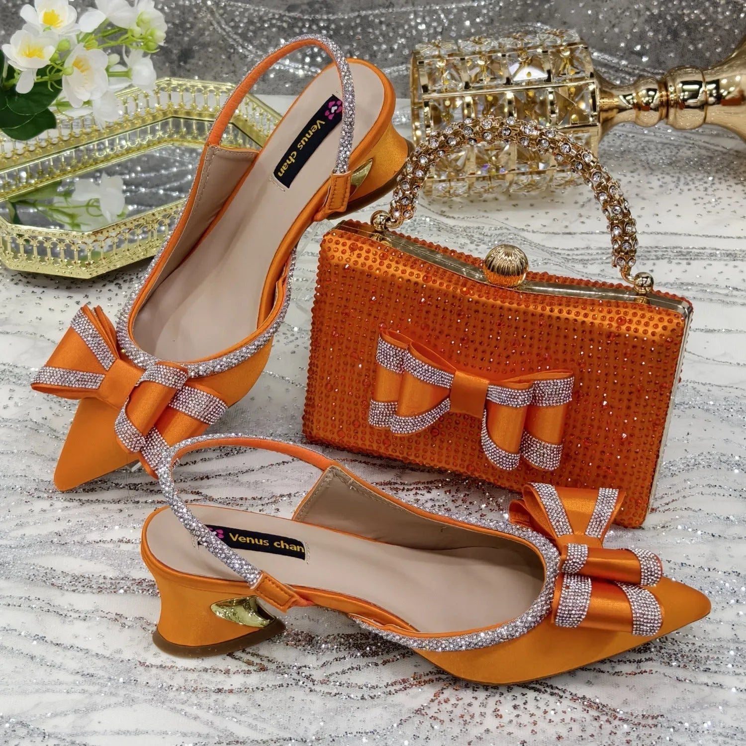 Women's black pointed toe sandals with a mid heel and matching rhinestone bag on a white background.