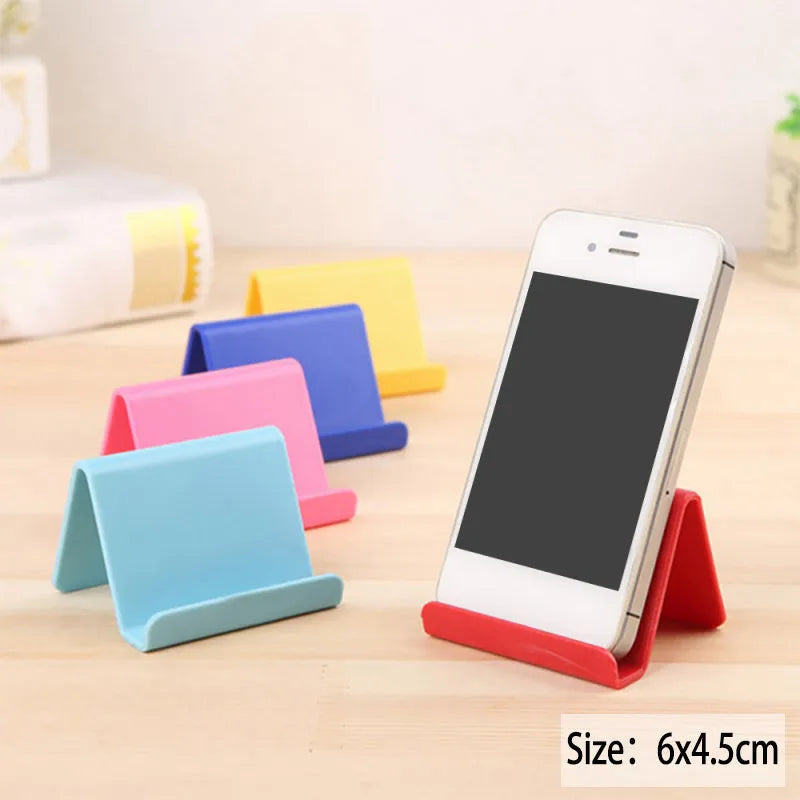 Small plastic mobile phone stand in blue, size 6x4.5cm, on a wooden desk