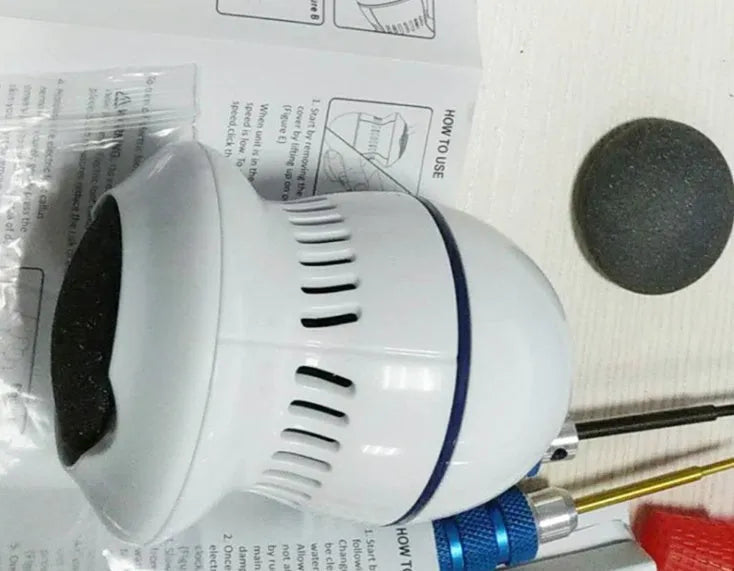 Beige and white electric foot file grinder with USB cable, two grinding heads, and cleaning brush
