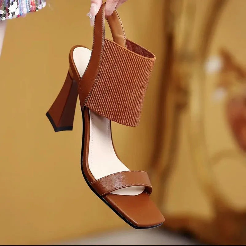 Women's black high heel sandals with elastic straps, showing side profile on a plain background.