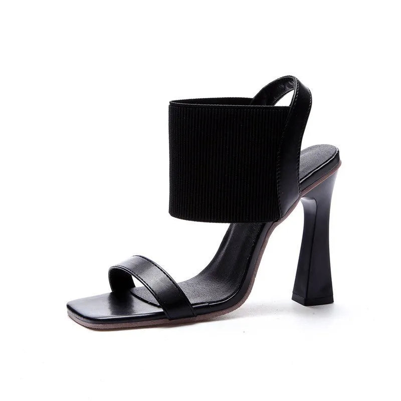 Women's black high heel sandals with elastic straps, showing side profile on a plain background.