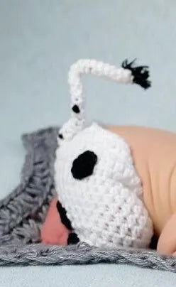 White hand-knitted baby cow suit set with matching hat and trousers for newborns.