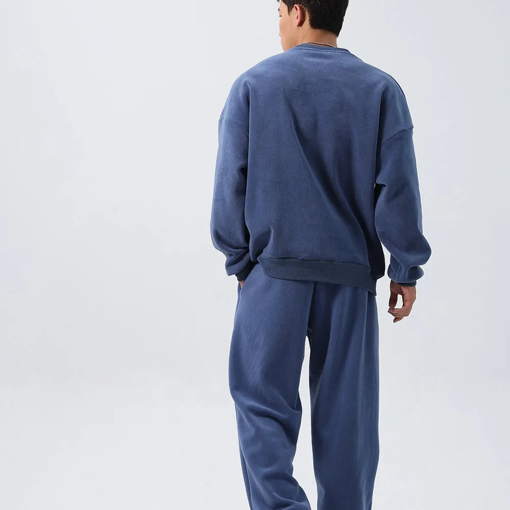 Men's black loose fit polar fleece winter sports suit with long sleeve coat and trousers on a hanger.