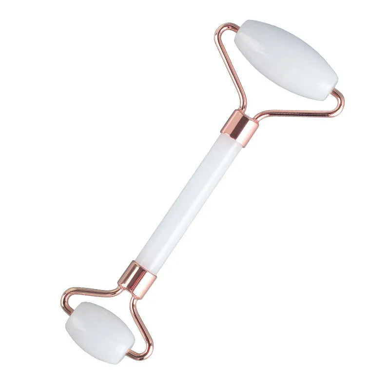 White jade facial roller and gua sha scraping tool set presented on a wooden board.