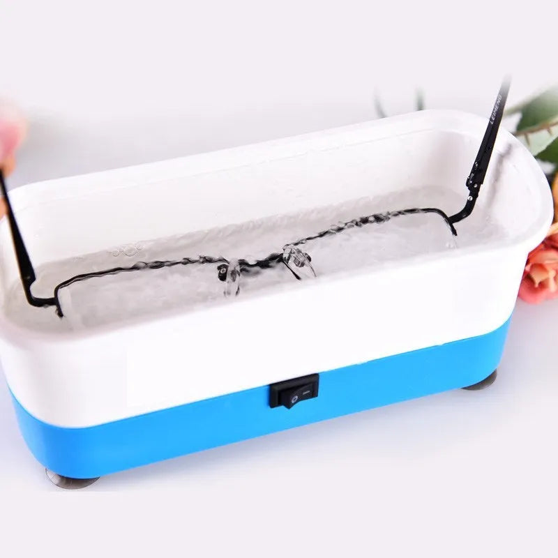 Analog ultrasonic cleaner in blue plastic casing with battery compartment and suction cups for cleaning glasses and contact lenses