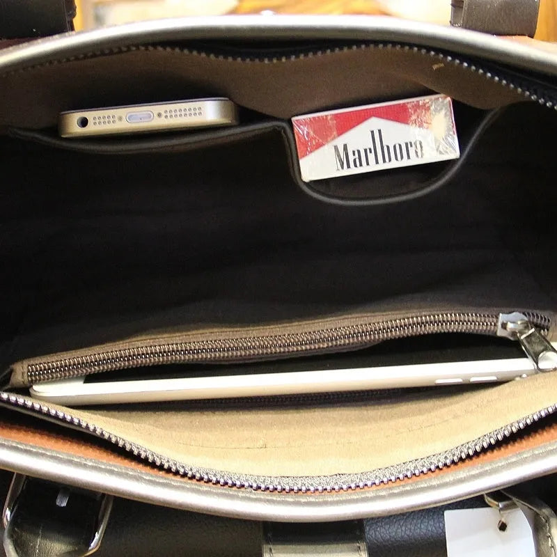 Men's cowhide leather brown business messenger bag with zip closure and shoulder strap on a wooden table