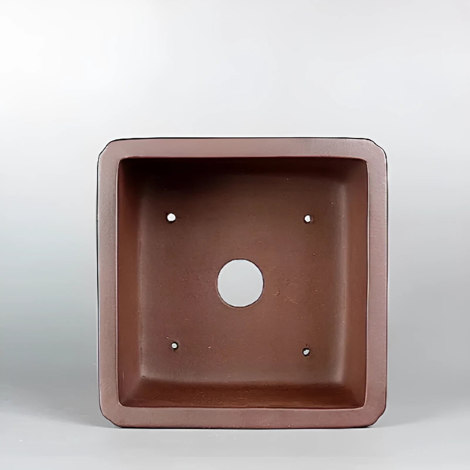 Brown handmade antique purple clay flower pot for plants on a windowsill.