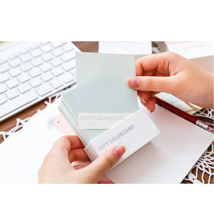 Set of rectangular paper memo notecards in four colour styles, shown with a pen, next to the OPP storage bag.