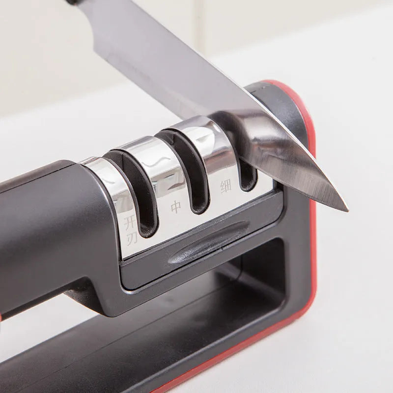 Professional three-stage knife sharpener in black with red trim, showing coarse, ceramic and fine abrasive slots.