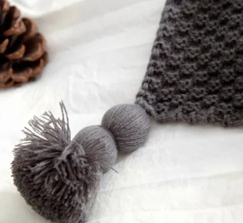 Nordic style fringed knit ball acrylic throw blanket in beige colour on a sofa.