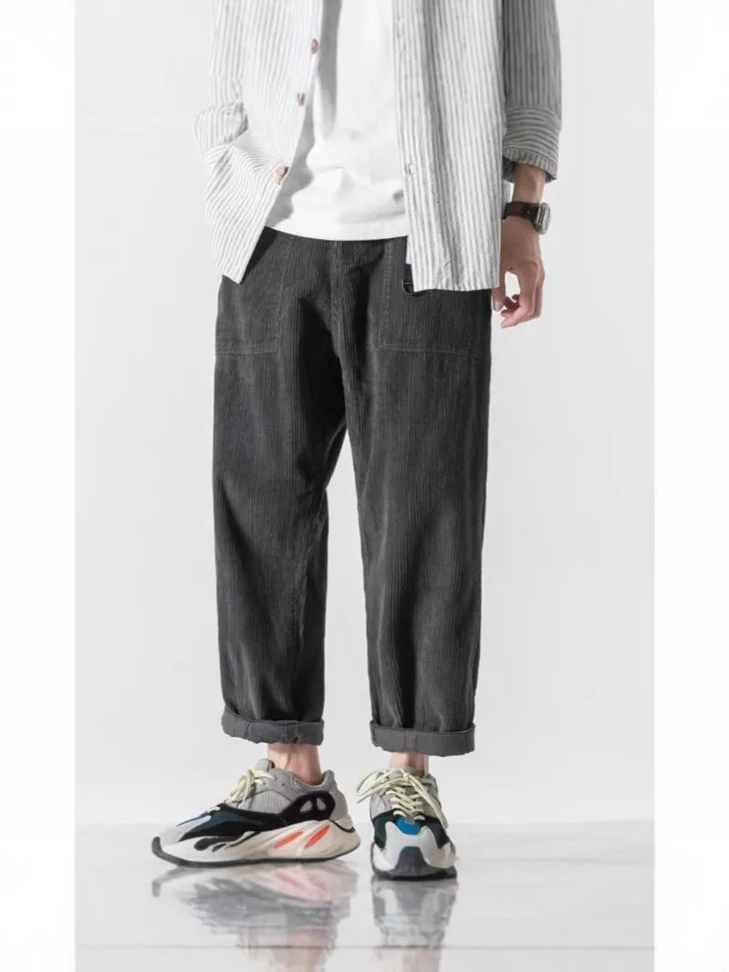 Man wearing loose straight-leg tapered trousers in dark grey, showing the full length and relaxed fit.