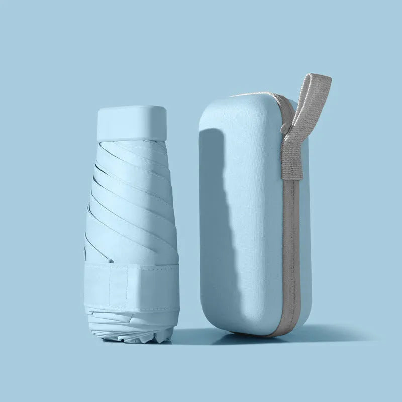 Ultra-light six-fold flat sun umbrella in sky blue with a rubber handle, shown with its capsule storage box.