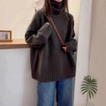 A woman wearing a thick, loose grey turtleneck sweater with a textured curling pile collar.