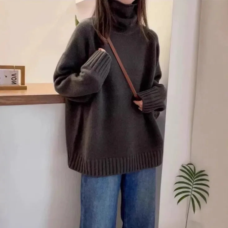 A woman wearing a thick, loose grey turtleneck sweater with a textured curling pile collar.