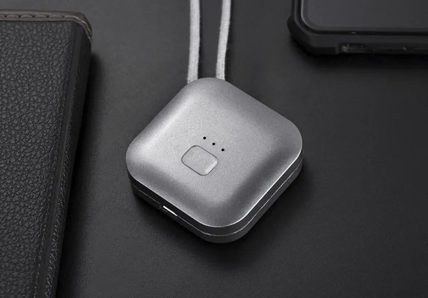 Compact pink USB portable air purifier necklace on a table with charging cable.