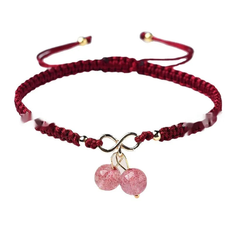 Women's bracelet with a natural strawberry quartz cherry charm on a black elasticated string.