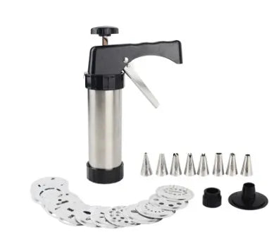 Stainless steel biscuit press gun with assortment of cookie moulds and piping nozzles on a baking sheet.