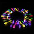 Water drop shaped solar LED fairy lights hanging outdoors with solar panel and ground spike.