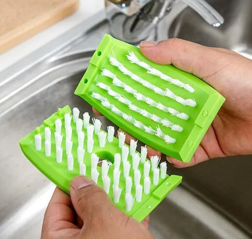Blue kitchen cleaning brush with slots for utensils and a suction cup on a white wall.