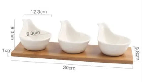 Porcelain ceramic dried fruit dish with three snack compartments on a wooden serving board.