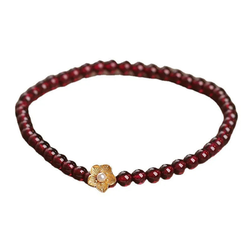 Red stone bead string bracelet with yellow flower accessories on wrist