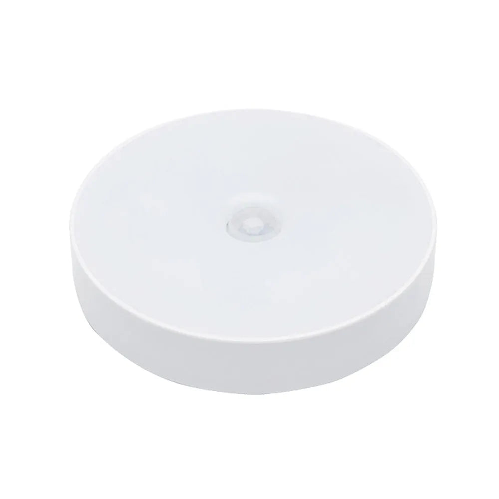 Small round beige and white LED motion sensor night light with USB charging cable.