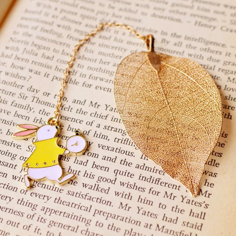KC alloy bookmark charms showing Alice, Rabbit, Clock, and Leaf designs on kraft cardboard packaging